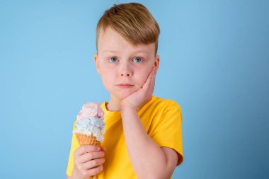 Üzgün çocuk yanağını tuttu ve keskin bir diş ağrısı hissetti. Elinde dondurma tutan bir çocuk. Diş bakımı, sağlık hizmeti konsepti. Yüksek kalite fotoğraf