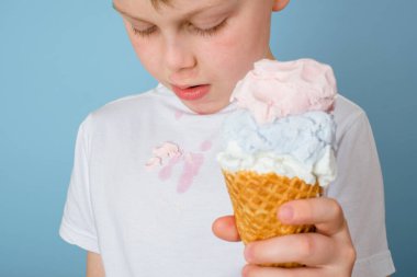 Mavi arka plandaki çocuk tişörtündeki kirli dondurma lekelerini kapat. Günlük yaşam lekesi ve temizlik konsepti 