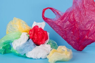 Mavi arka planda plastik torbalar ve farklı renklerde plastik ambalajlar. plastik konsept yok