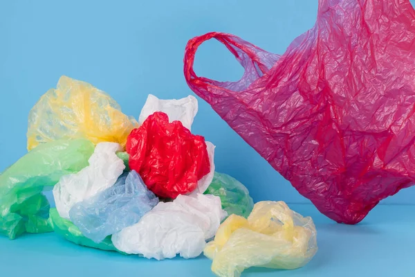 Mavi arka planda plastik torbalar ve farklı renklerde plastik ambalajlar. plastik konsept yok