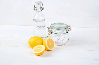 Baking soda in jar, vinegar, lemon on a white background. The concept of removing stains on clothes 