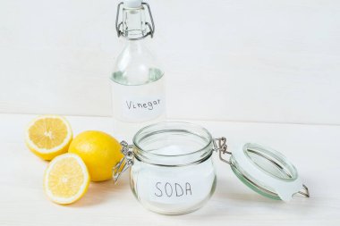 Baking soda in jar, vinegar, lemon on a white background. The concept of removing stains on clothes 