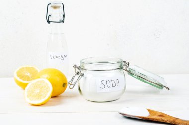 Baking soda in jar, vinegar, lemon, wooden spoon on a white background. The concept of removing stains on clothes. High quality photo