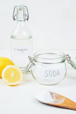 Baking soda in jar, vinegar, cut lemon, wooden spoon on a white background. The concept of removing stains on clothes. High quality photo