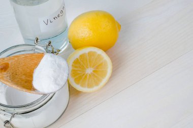 Open jar of baking soda with a wooden spoon on top, vinegar, cut lemon. top view, space for text. The concept of organic removing stains on clothes. High quality photo