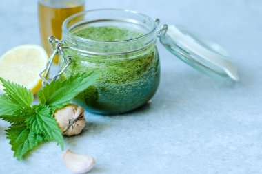Vejetaryen ısırgan otu, sarımsak, zeytinyağı, limon ve ceviz. Gri arka planda ev yapımı ısırgan otu pesto kavanozu. Vejetaryen ısırgan otu sosu. Yüksek kalite fotoğraf