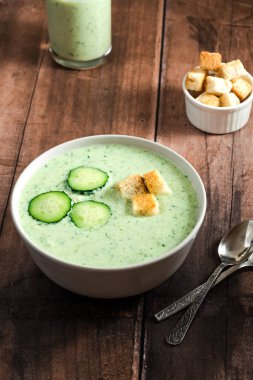 Yeşil taze soğuk çorba, salatalık dilimi ve ahşap bir masada kızarmış ekmek. sağlıklı vejetaryen yemeği. Yüksek kalite fotoğraf