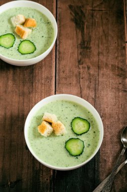 Yeşil taze soğuk çorba, salatalık dilimi ve ahşap masa manzaralı kızarmış ekmek. sağlıklı vejetaryen yemeği. Yüksek kalite fotoğraf