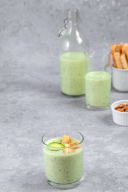 Fındıklı, otlu, yoğurtlu soğuk salatalık çorbası gri arka planda cam bir kapta kraker. sağlıklı vejetaryen yemeği. Yüksek kalite fotoğraf