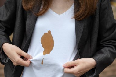 Beyaz elbiselerde kirli kahve lekesi gösteren kadın elleri. Açık havada. Kıyafetlerdeki leke temizleme konsepti. Yüksek kalite fotoğraf