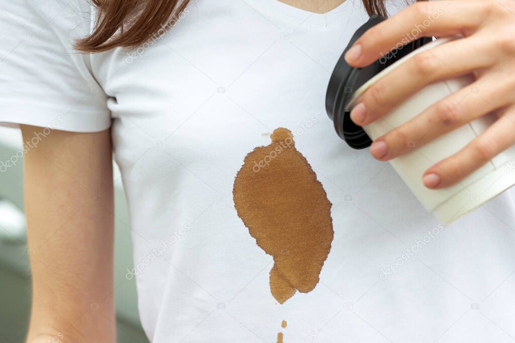 Coffee stain. Unrecognizable girl girl spilling hot coffee on herself. The concept of cleaning stains on clothes. High quality photo