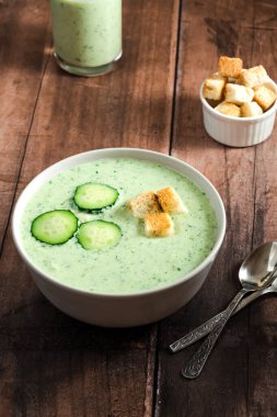 Yeşil taze soğuk çorba, salatalık dilimi ve ahşap bir masada kızarmış ekmek. sağlıklı vejetaryen yemeği. Yüksek kalite fotoğraf