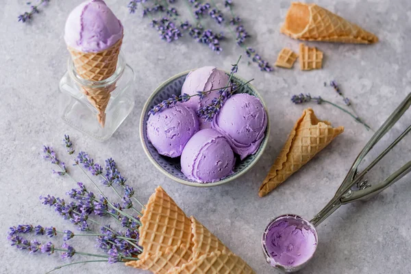 Creamy balls vegan lavender ice cream in plates with flowers French lavender, an ice cream scoop on a gray background. flat lay, top view. High quality photo