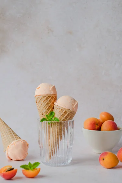 Vegan apricot ice cream made with coconut cream, fresh apricots and mint in the horn. Summer seasonal cold sweet healthy vegan dessert. High quality photo