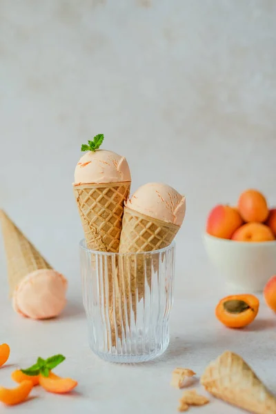Creamy vegan apricot ice cream in the horn in a glass, styling mint leaves on top. Summer seasonal cold sweet healthy vegan dessert. High quality photo