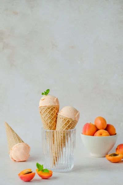 Vegan apricot ice cream made with coconut cream, fresh apricots and mint in the horn. Summer seasonal cold sweet healthy vegan dessert. High quality photo
