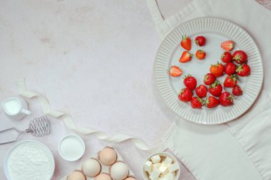 Yaz pişirme malzemeleri: Çilek, un, süt, yumurta, şeker, tereyağı, önlükteki yumurta çırpmak için çırpma. Tatlı hamur işleri. Üst Manzara. Yüksek kalite fotoğraf
