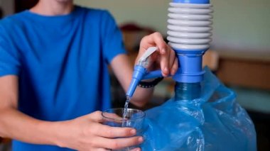 An unrecognizable child drinking-water from a table cooler. High quality 4k footage