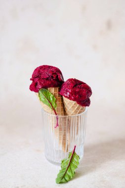 Pembe arka planda gözleme külahında vejetaryen pancar dondurması. Taze pancar yapraklı stil. Sağlıklı vejetaryen dondurulmuş tatlı. Yüksek kalite fotoğraf