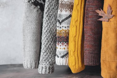 Elinde güz mevsiminde sıcak örülmüş kazaklar tutan bir kadın. Mevsim ve gardırop değişikliği. Sonbahar yavaş moda konsepti. Yüksek kalite fotoğraf