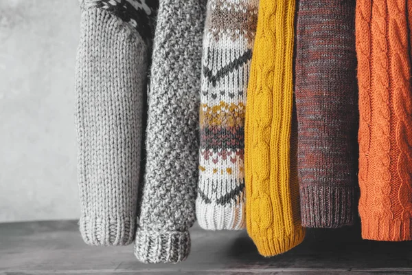 Gri bir arka planda, sonbahar paletinde örülmüş kazak kolları asılı. kullanılmış kazaklar. Ekolojik ve sürdürülebilir moda. - Evet. Yüksek kalite fotoğraf