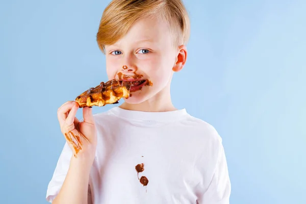Criança Está Comendo Waffle Belga Com Molho Chocolate Fundo Azul — Fotografia de Stock