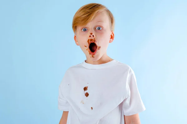 Roztomilý Překvapený Chlapec Čokoládou Tváři Oblečení Dívá Kamery Izolované Modrém — Stock fotografie