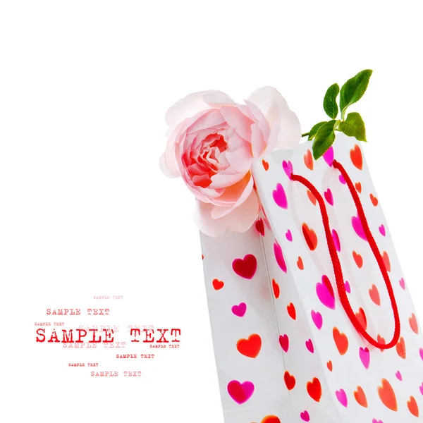 White gift bag with heart pattern and pink rose on white backg — Stock Photo, Image