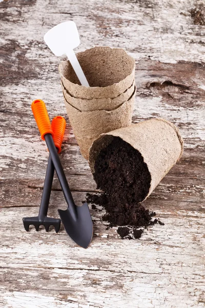 Garden tools (shovel, rake, peat pots ) on old wooden background — Stock Photo, Image