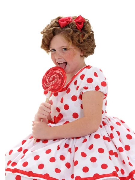 Een meisje een rode lolly likken — Stockfoto