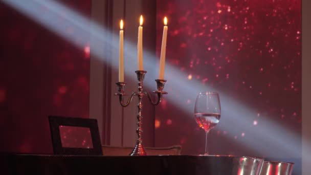 キャンドルスティック3本と赤光沢のある背景にワインのガラス — ストック動画