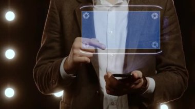 Businessman activates conceptual HUD hologram on smartphone with text 24h news. Man in a white shirt and jacket with a holographic screen on the background of lights