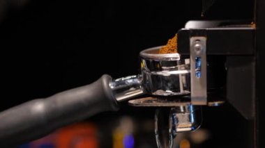 Barista kahve öğütücüsünde taze kahve çekirdeği öğütüyor. Kahve dükkanında sıcak bir içecek hazırlıyor. Yakın plan.