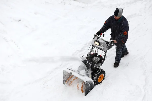 Hombre empujando soplador de nieve Imagen de archivo