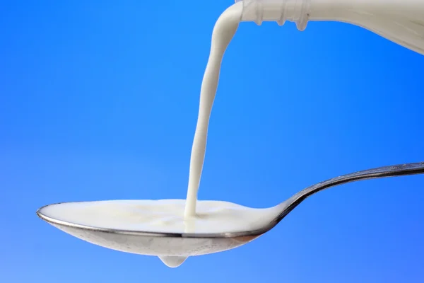 Pouring milk to the spoon — Stock Photo, Image