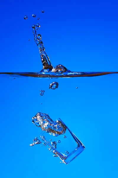 Glas fällt ins Wasser, spritzt — Stockfoto