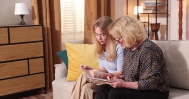 Küçük torun, büyükannesine kredi kartıyla alışveriş yapmayı öğretiyor ve dizüstü bilgisayarını işaret ediyor.