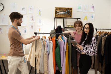 Moda tasarımcılarının ve terzilerin işi. Moda tasarımcıları stüdyolarında çalışıyor. Renkli Kumaşlar, Giysiler Asılma ve Dikiş Ögeleri Görünür.