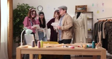 Moda tasarımcılarının ve terzilerin işi. Moda tasarımcıları stüdyolarında çalışıyor. Renkli Kumaşlar, Giysiler Asılma ve Dikiş Ögeleri Görünür