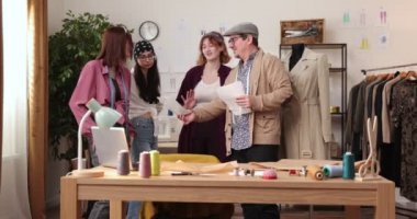Moda tasarımcılarının ve terzilerin işi. Moda tasarımcıları stüdyolarında çalışıyor. Renkli Kumaşlar, Giysiler Asılma ve Dikiş Ögeleri Görünür
