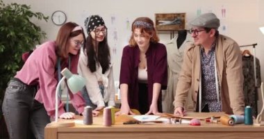 Moda tasarımcılarının ve terzilerin işi. Moda tasarımcıları stüdyolarında çalışıyor. Renkli Kumaşlar, Giysiler Asılma ve Dikiş Ögeleri Görünür