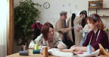 Moda tasarımcılarının ve terzilerin işi. Moda tasarımcıları stüdyolarında çalışıyor. Renkli Kumaşlar, Giysiler Asılma ve Dikiş Ögeleri Görünür