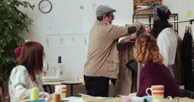 Moda tasarımcılarının ve terzilerin işi. Moda tasarımcıları stüdyolarında çalışıyor. Renkli Kumaşlar, Giysiler Asılma ve Dikiş Ögeleri Görünür