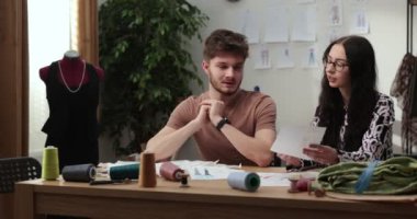 Moda tasarımcılarının ve terzilerin işi. Moda tasarımcıları stüdyolarında çalışıyor. Renkli Kumaşlar, Giysiler Asılma ve Dikiş Ögeleri Görünür