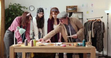 Moda tasarımcılarının ve terzilerin işi. Moda tasarımcıları stüdyolarında çalışıyor. Renkli Kumaşlar, Giysiler Asılma ve Dikiş Ögeleri Görünür.