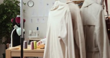 Moda tasarımcılarının ve terzilerin işi. Moda tasarımcıları stüdyolarında çalışıyor. Renkli Kumaşlar, Giysiler Asılma ve Dikiş Ögeleri Görünür.