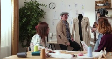 Moda tasarımcılarının ve terzilerin işi. Moda tasarımcıları stüdyolarında çalışıyor. Renkli Kumaşlar, Giysiler Asılma ve Dikiş Ögeleri Görünür.