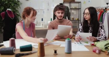 Moda tasarımcılarının ve terzilerin işi. Moda tasarımcıları stüdyolarında çalışıyor. Renkli Kumaşlar, Giysiler Asılma ve Dikiş Ögeleri Görünür.