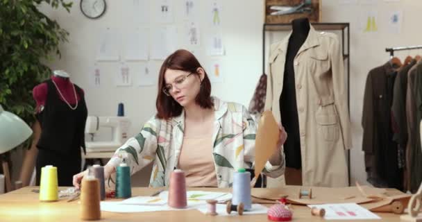 El trabajo del diseñador de moda y sastres en la tienda. Diseñadores de moda trabajando en su estudio. Tejidos coloridos, ropa colgante y artículos de costura son visibles. — Vídeo de stock