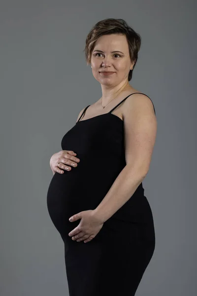 Portrét těhotné ženy. Těhotná šťastná žena dotýká břicho, dělat focení v ateliéru — Stock fotografie